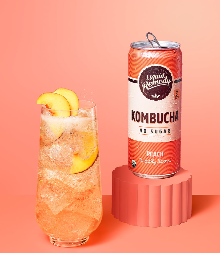 Liquid Remedy Peach Kombucha Can with Glass Lifestyle