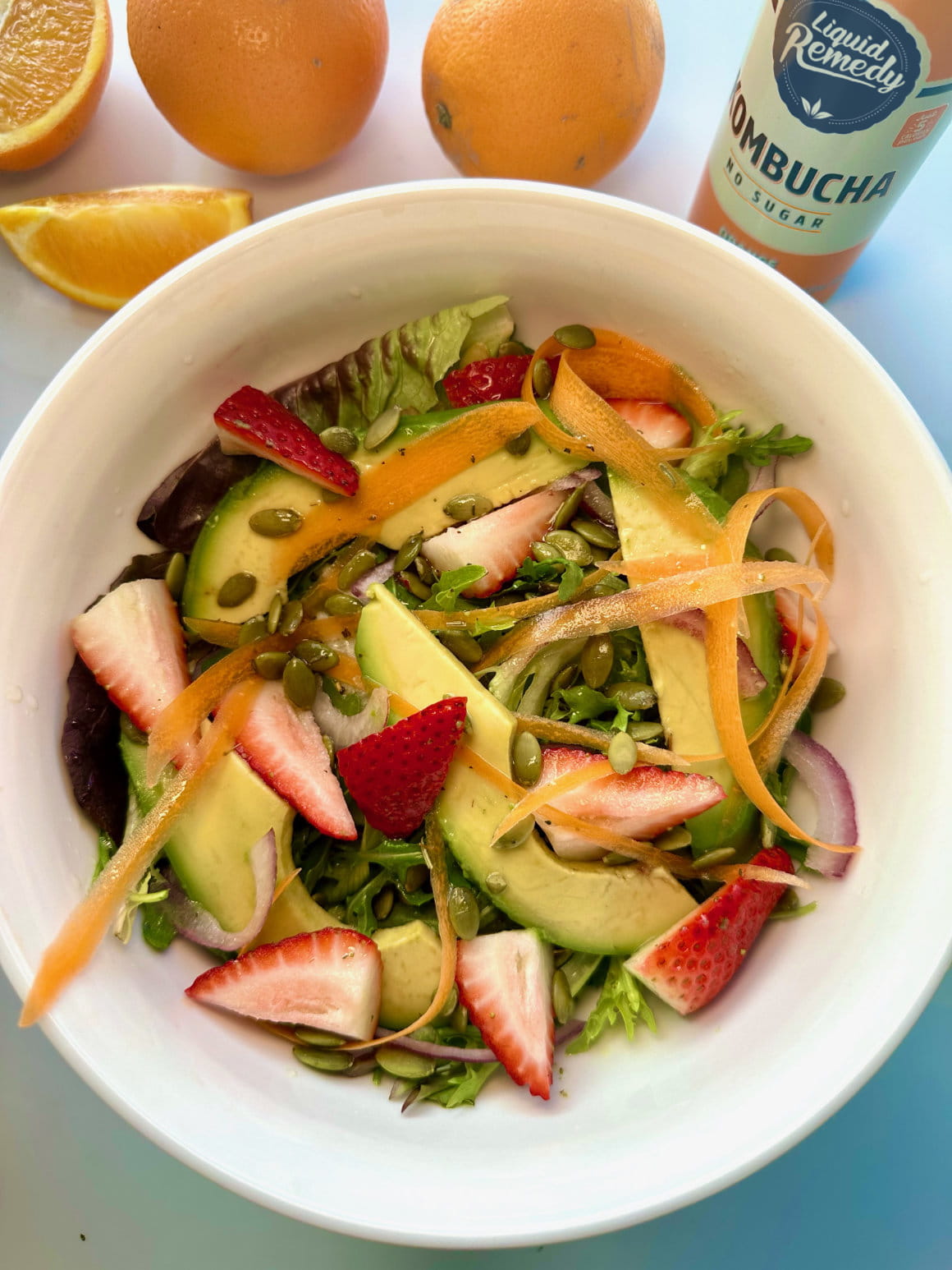 Liquid Remedy Orange Splash Kombucha next to a salad